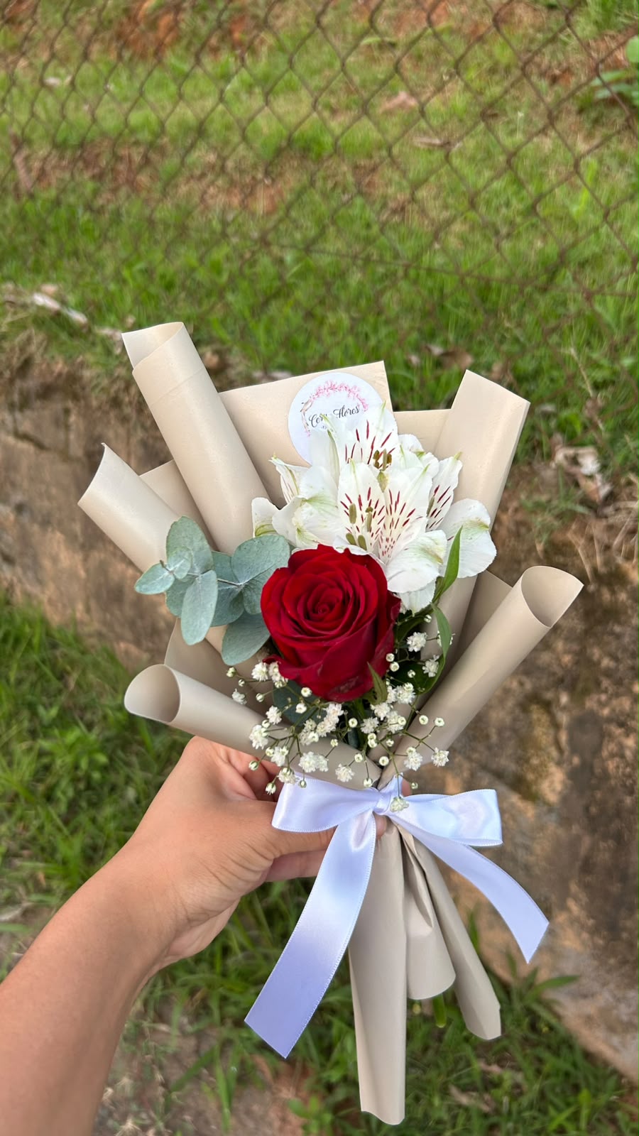 Mini buquê com uma rosa vermelha, alstroemérias brancas, eucalipto e mosquitinho em papel bege com laço branco